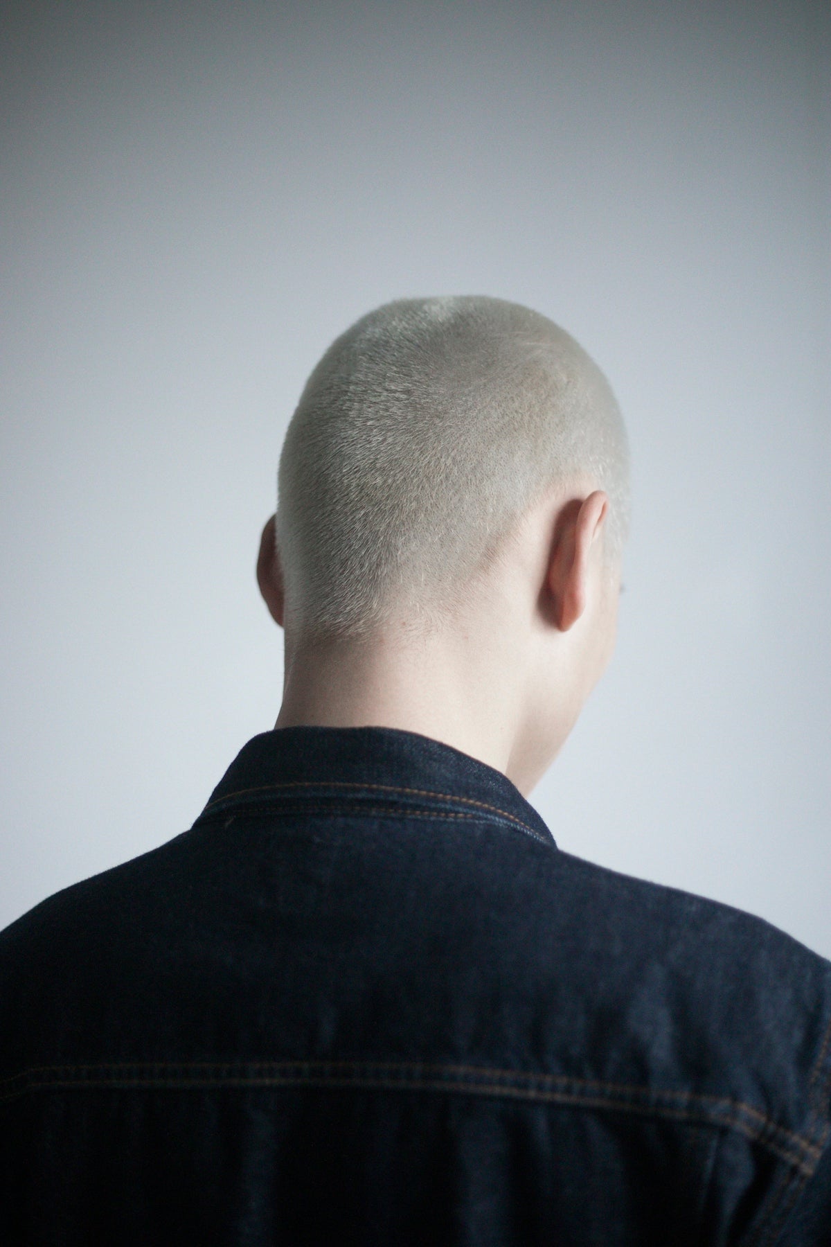 a man with a shaved head and a denim jacket