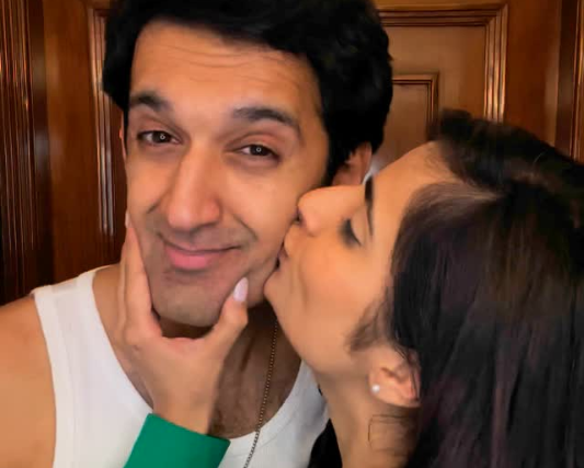 Person kissing another person on the cheek with a wooden door in the background